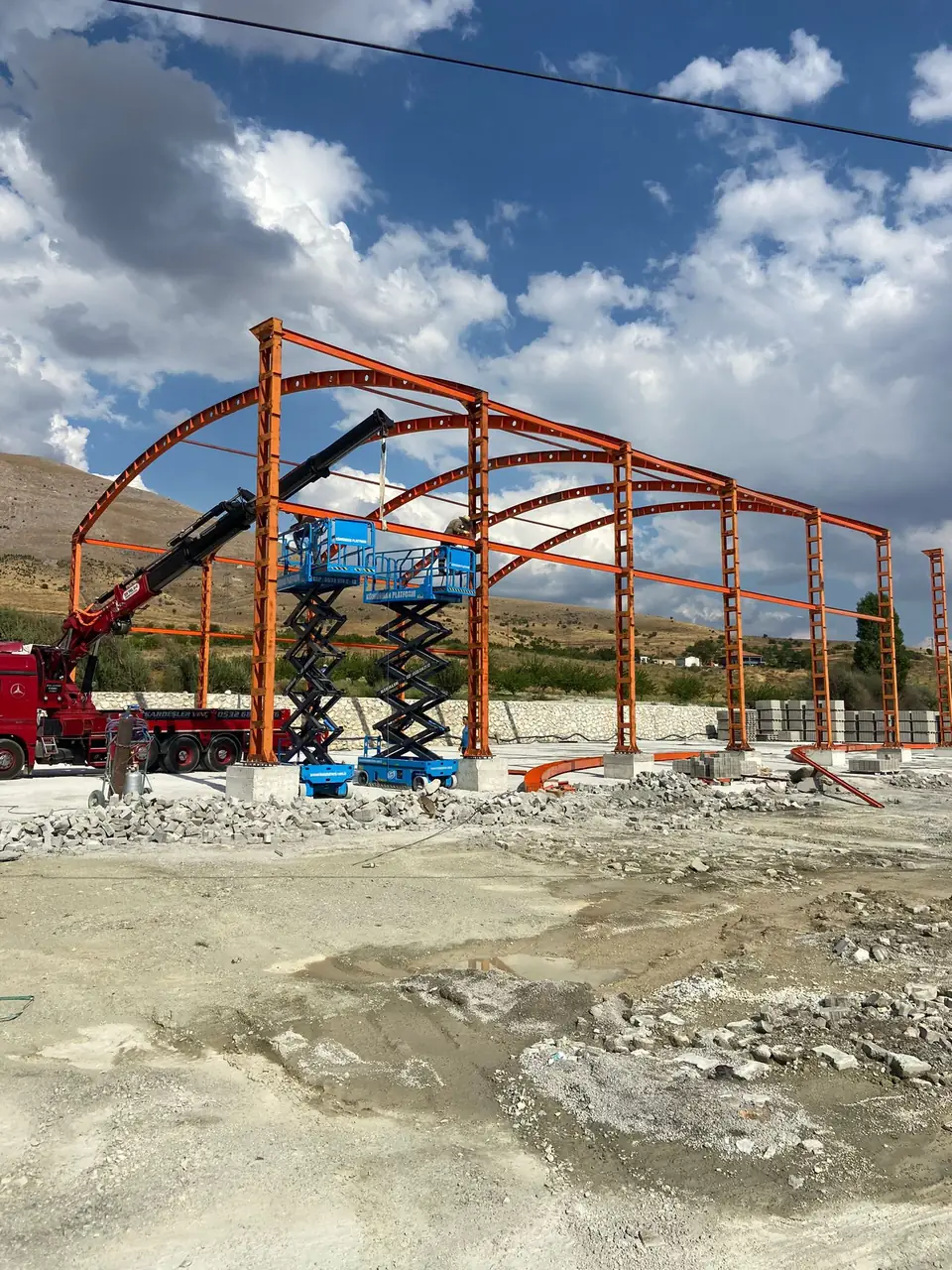 Hangar çelik iskeletinin yandan görünümü, makaslı platformlar ve vinç